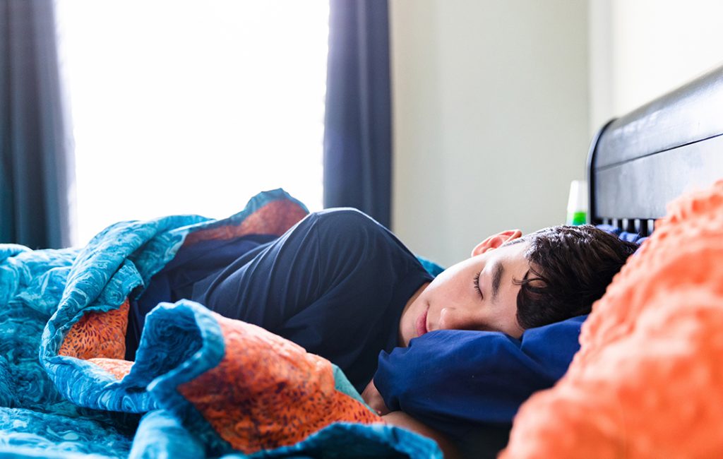 Teen boy sleeping in bed