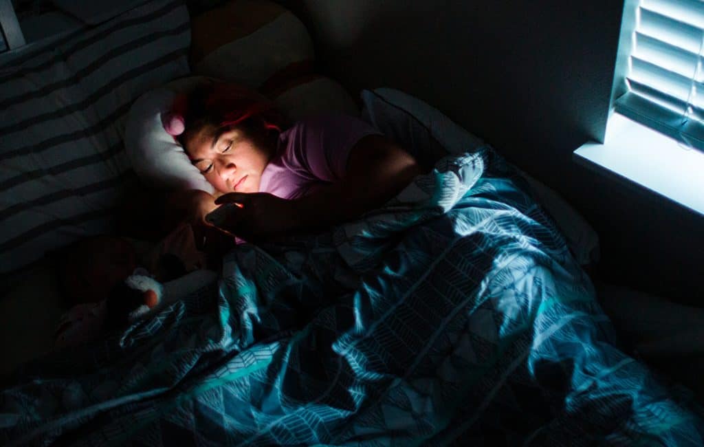 Woman reading phone in bed