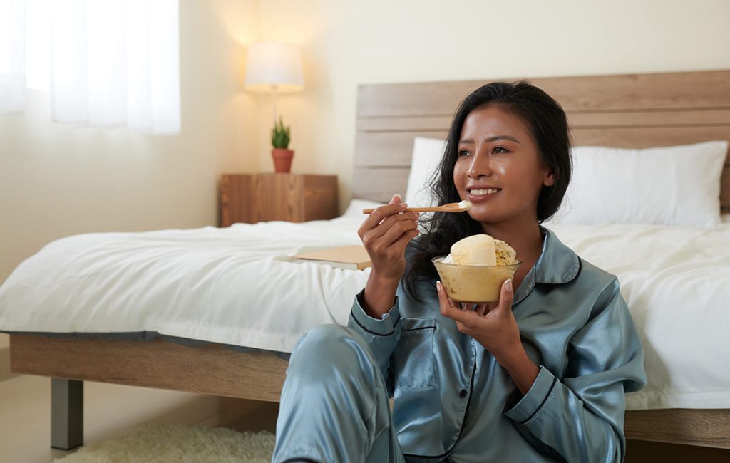 woman eating ice cream in bed