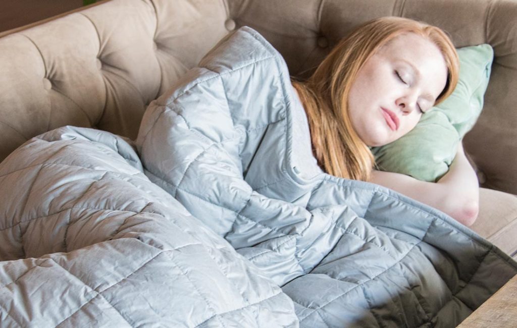 Woman sleeping on couch under blanket