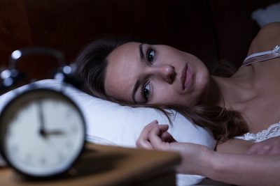 Woman with sleep anxiety looking at watch