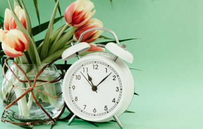 Vase of tulips next to a white clock
