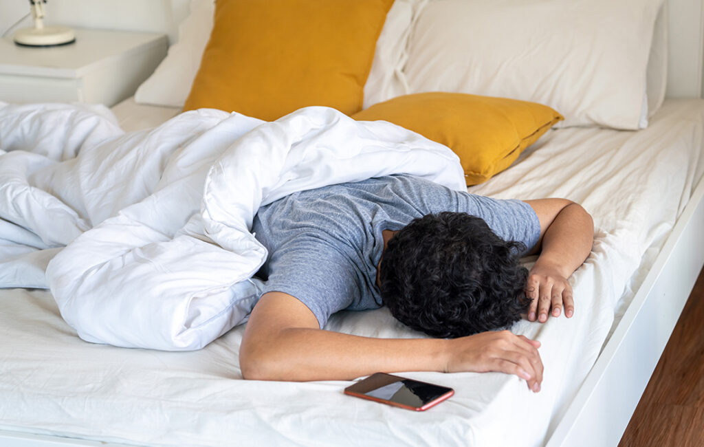 Man sleeping facedown in bed