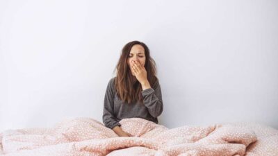 why do I wake up tired - woman yawning in bed