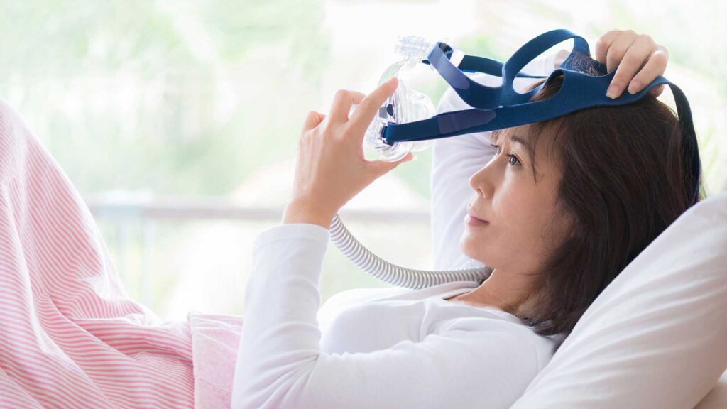 woman putting on CPAP device