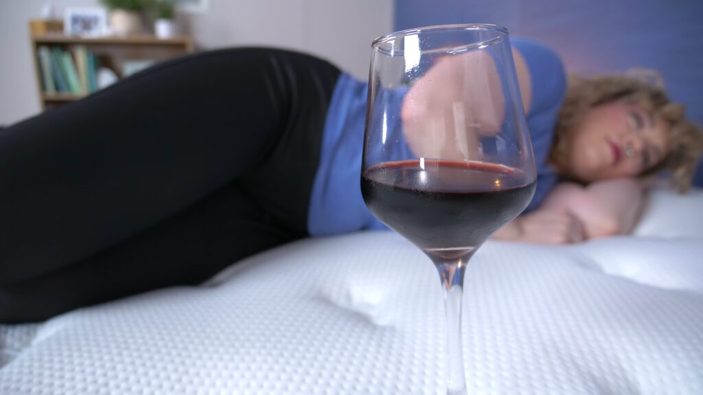 A woman lying next to a glass of red wine to test the mattress's motion isolation.