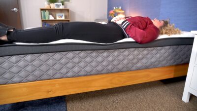 A woman lying near the edge of a mattress to test out its edge support.