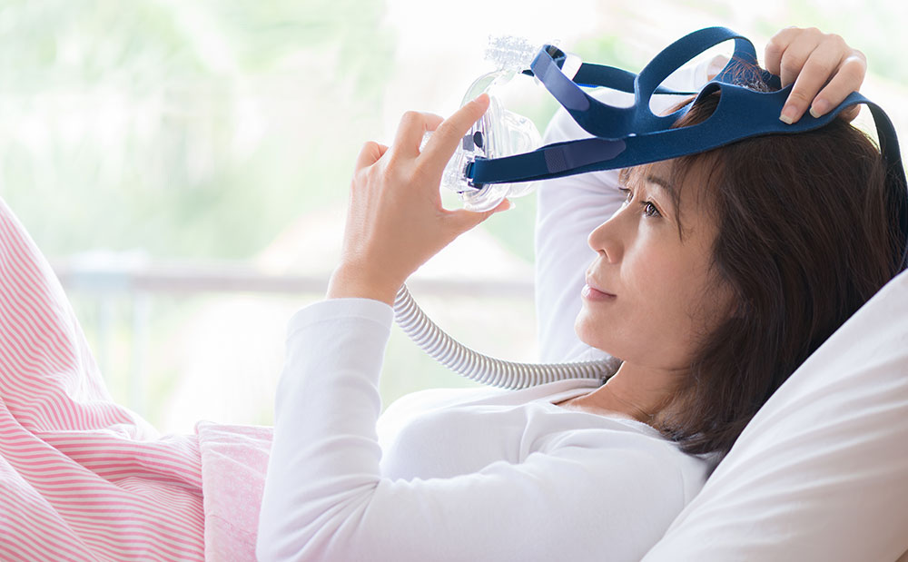 woman putting on CPAP mask