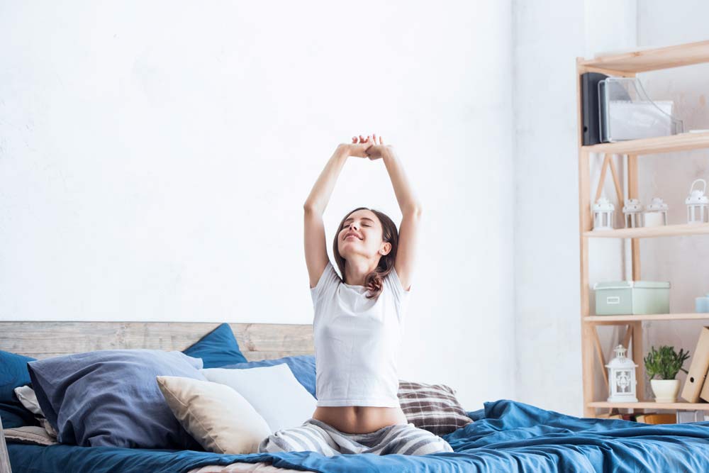 woman stretching in bed after good night's sleep from following a bedtime routine