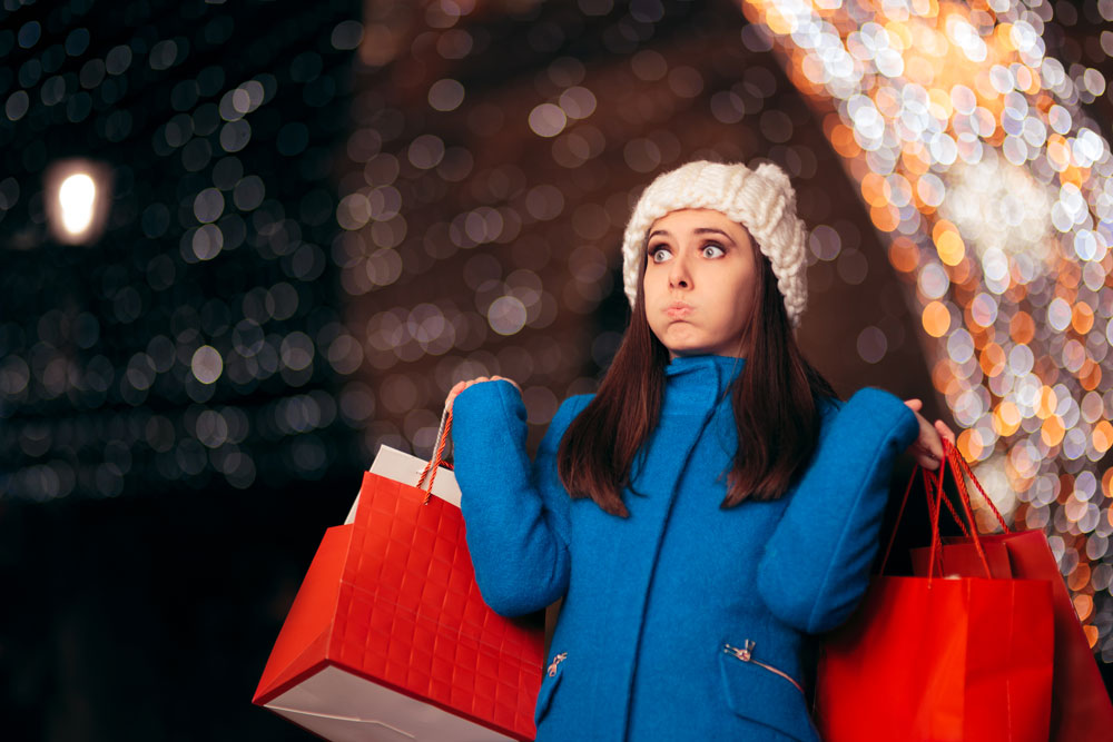 tired girl holding shopping bags on christmas lights décor