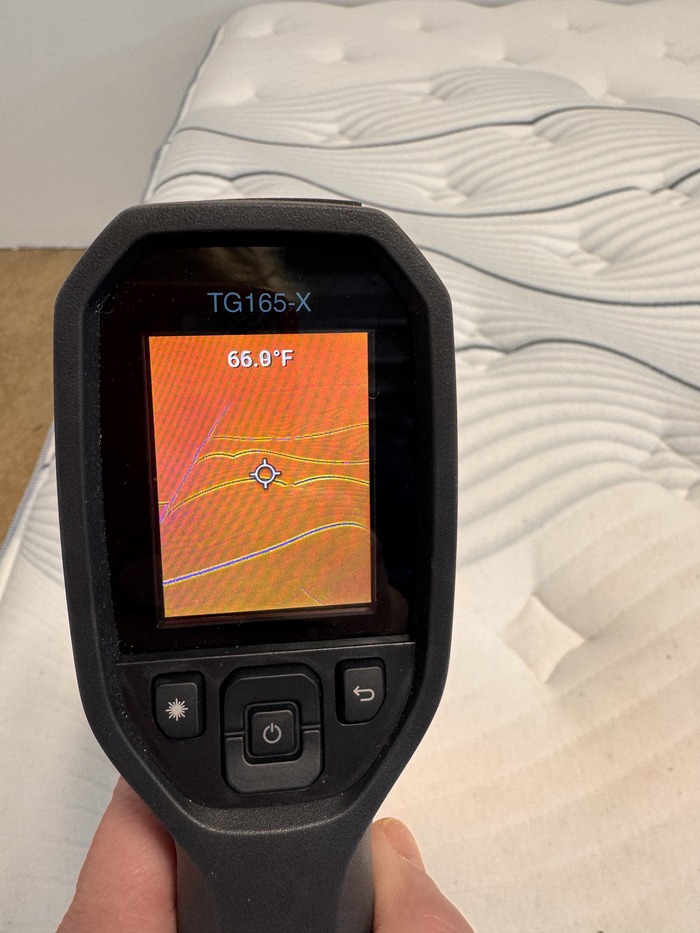 A closeup of a thermal gun reading of the Bear Elite Hybrid mattress, displaying 66 degrees on its screen.