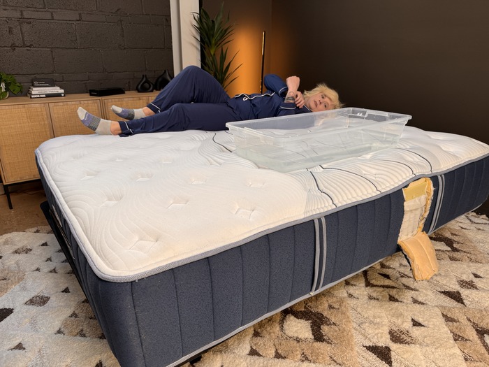 A woman lying on the Bear Elite Hybrid mattress next to a bin full of water.