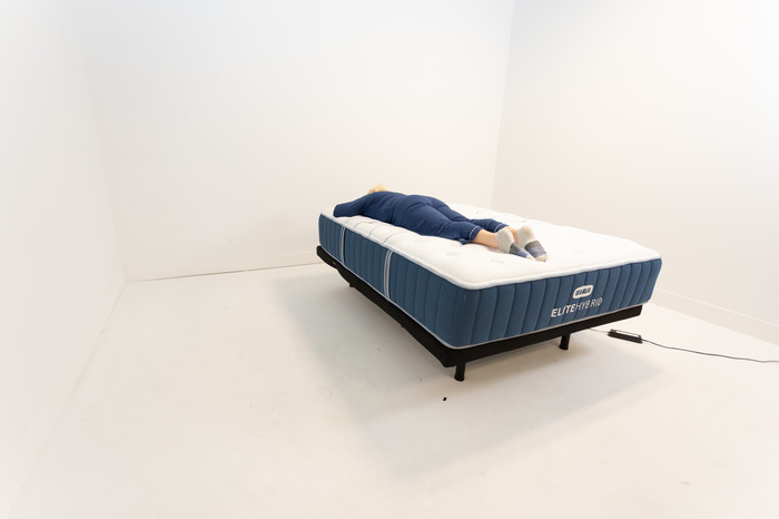 A person is shown stomach sleeping on the Bear Elite Hybrid mattress.