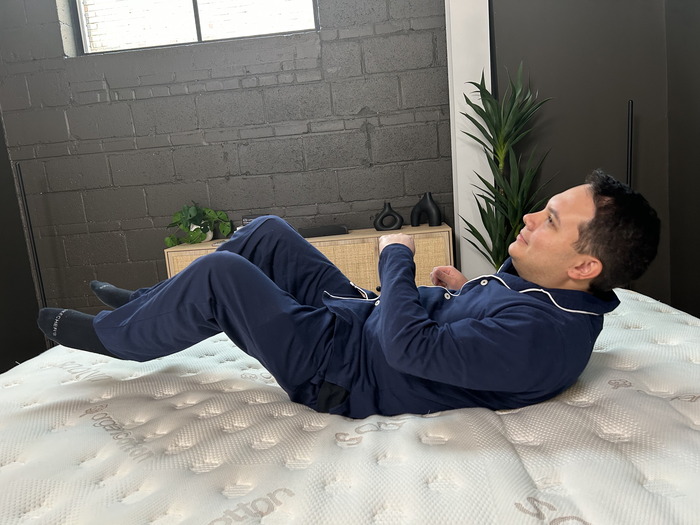 A man rolling around on a Saatva mattress to test its responsiveness.