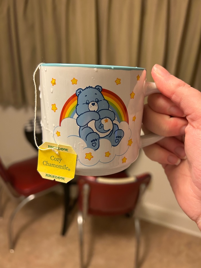 Our tester holds up a Care Bear mug full of Bigelow Cozy Chamomile Tea.