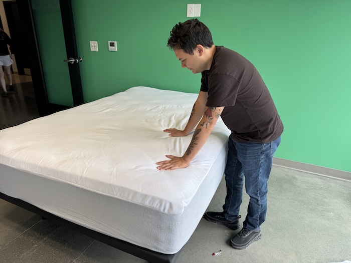 Our tester leans over a freshly-installed Casper Waterproof Mattress Protector