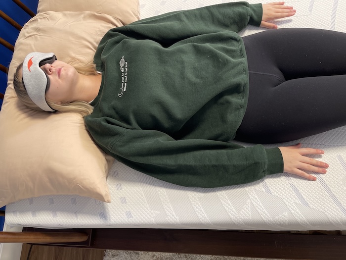 A woman wearing an eye mask and lying on her back on the Bodipedic 12" mattress.