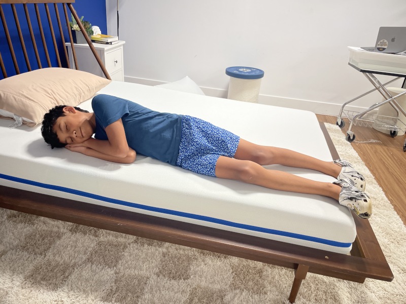 An adorable child laying on a Nectar Kids Mattress