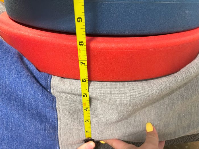 A stack of weights on top of a Casper The One mattress, with a tape measure measuring the sinkage.