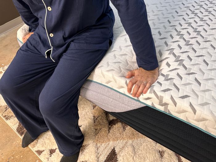 A man sits on the edge of the Nectar Premier mattress