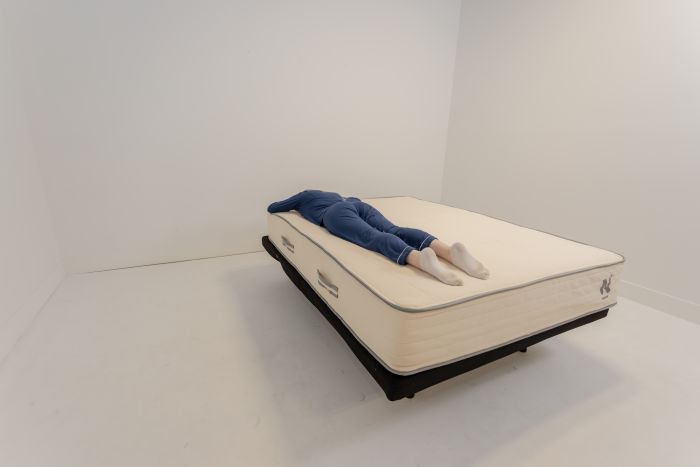 A woman stomach-sleeping on the Nolah Natural mattress.