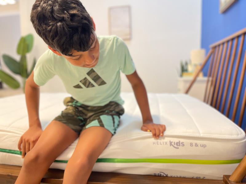 Our young tester performs a seated edge support test on the Helix Kids 8-Inch Mattress