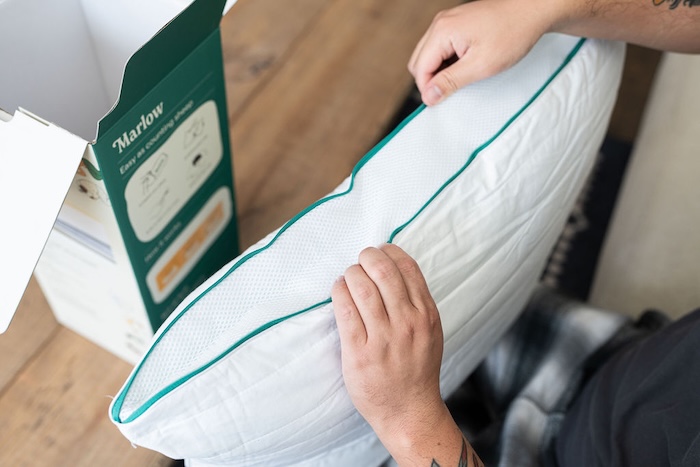 A man holds a Marlow Pillow upright, showing its side.