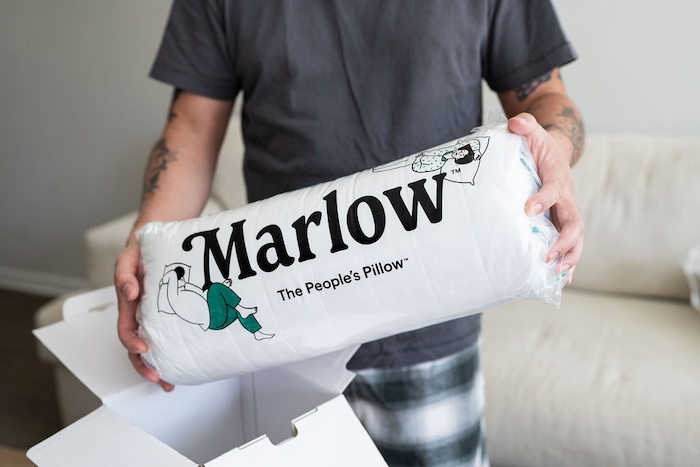 A man holds a Marlow Pillow still in its packaging.