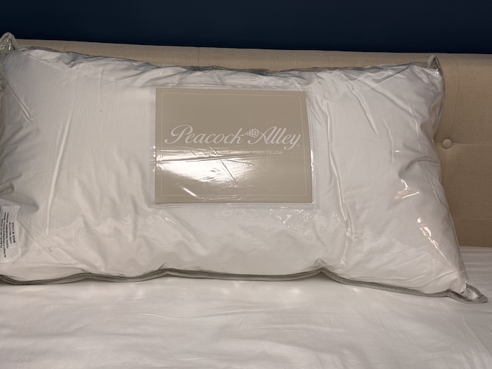 A Peacock Alley Down Alternative Pillow sitting on a bed in its packaging.