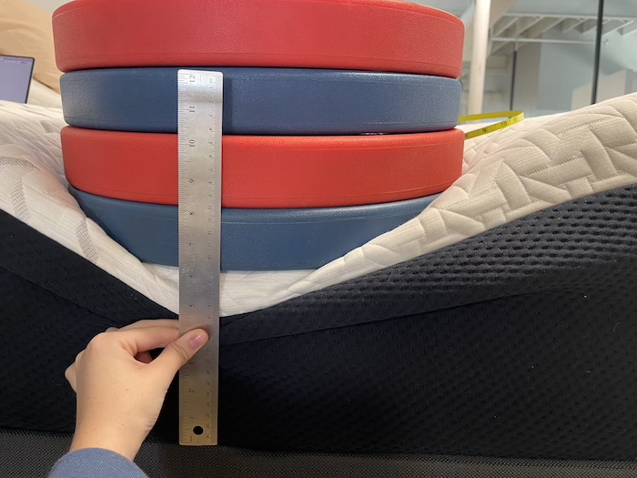 A stack of weights sitting on the edge of the Nectar Premier to test its support.