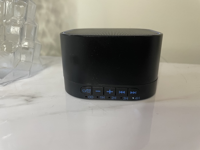 A closeup of a Magicteam Sound Machine sitting on a marble countertop.