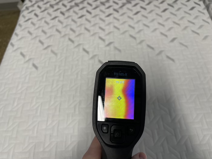 A closeup of a thermal gun reading the temperature of the Nectar Premier mattress after someone has rested on it for 5 minutes. The screen reads 73.9 degrees.