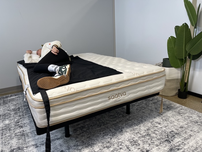 A woman lying on top of a pressure mat spread out across a Saatva mattress. She's in the side-sleeping position.