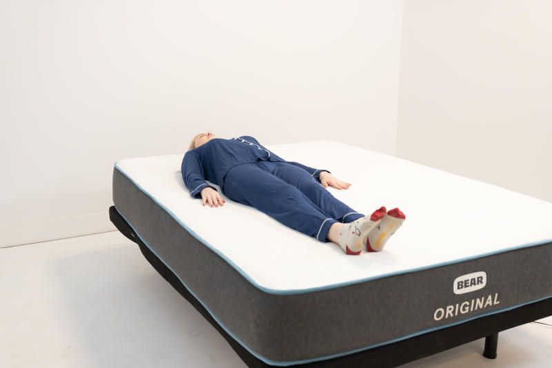 Sleep expert Riley Otis assessing the support of a Bear Original in a back-sleeping position.