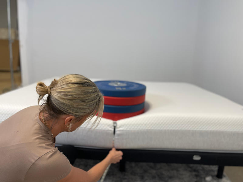 Our tester measuring weight plates on the edge of the Nolah Signature Mattress
