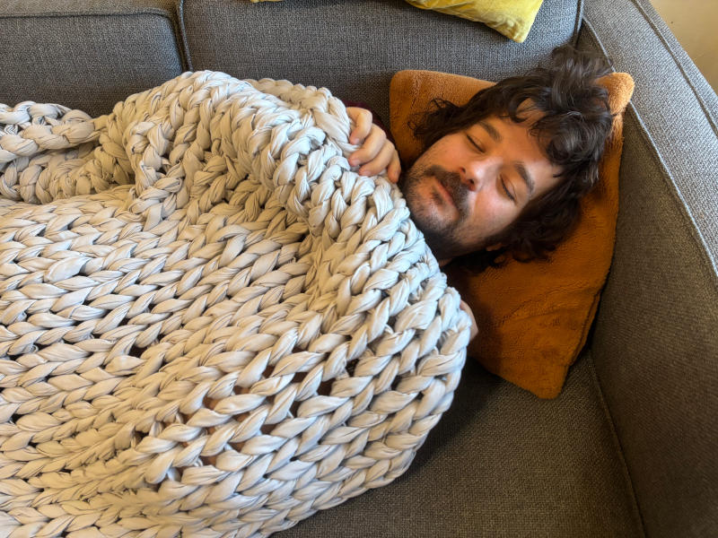 Our tester looking cozy on the couch with a Silk & Snow Handknitted Weighted Blanket