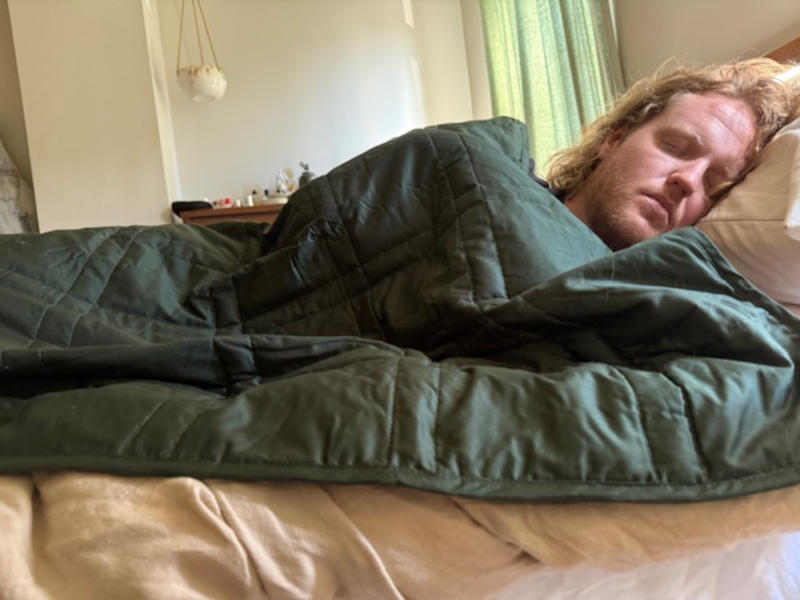 Our tester relaxes under a Baloo Living Weighted Throw Blanket