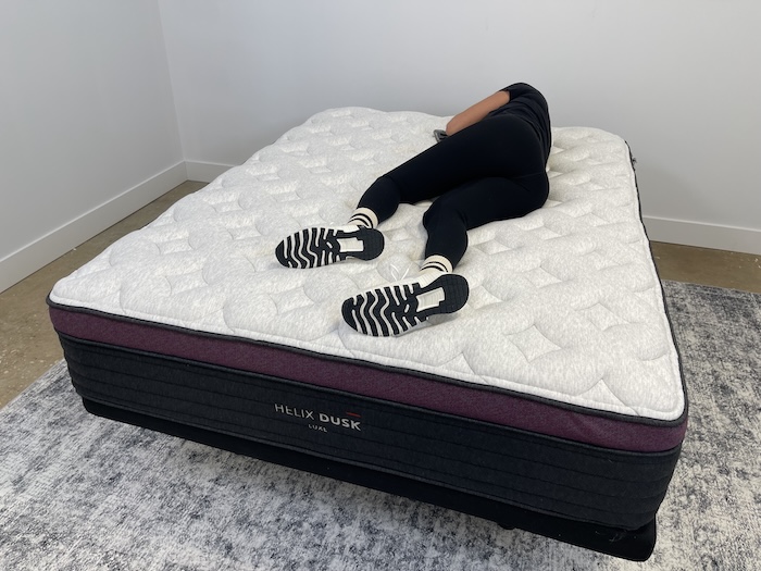 A woman lying on the Helix Dusk Luxe and rolling over to her side.